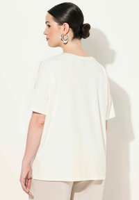 Cremefarvet t-shirt med afslappet pasform, korte ærmer og rund halsudskæring. Glat tekstur, casual design.