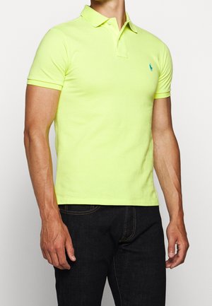Polo shirt giallo fluo realizzato in cotone, con colletto classico e maniche corte. Include un piccolo logo blu sul petto.