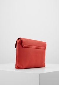 Borsa a pochette in pelle rossa con una finitura testurizzata, forma rettangolare e chiusura a patta. Il design presenta linee pulite e accenti minimi.