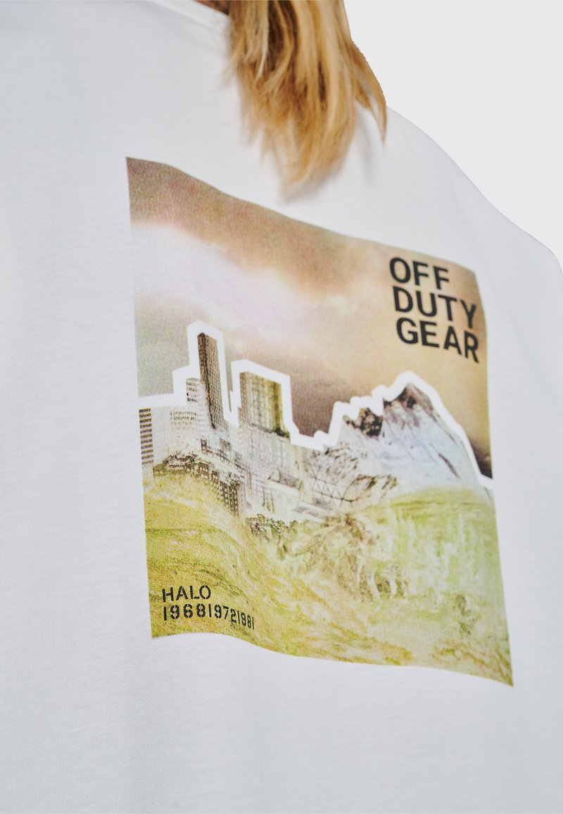 Grafik mit urbaner und bergiger Landschaft auf weißem Shirt mit dem Text "OFF DUTY GEAR" und den Zahlen "1968 1972 1981" in der Ecke.