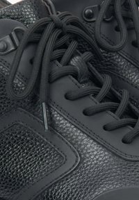 Czarne sneakersy o teksturowanym wykończeniu, okrągłych sznurowadłach, wzmocnionych oczkach i gładkiej paneli z boku dla dodatkowego akcentu.