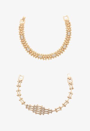 Dwie złote bransoletki z osadzonymi diamentami, zdobione misternymi wzorami z kulek i prętów, każda z unikalnym rodzajem zapięcia.