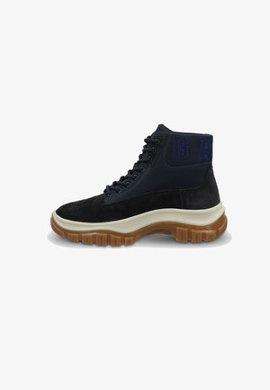 High-top sneakers with a navy and black suede upper, featuring blue embroidered "GA" details, a thick beige sole, and textured lacing.