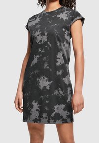 Schwarzes Baumwoll-T-Shirt-Kleid mit lockerer Passform, umgeschlagenen kurzen Ärmeln und einem Spritzmuster in verschiedenen Grautönen.