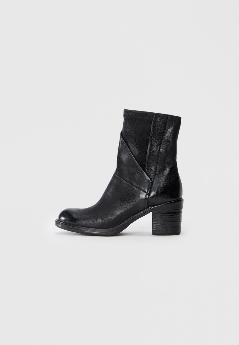Bottines en cuir noir avec un talon empilé et des coutures décoratives, présentées en vue de profil sur un fond blanc.