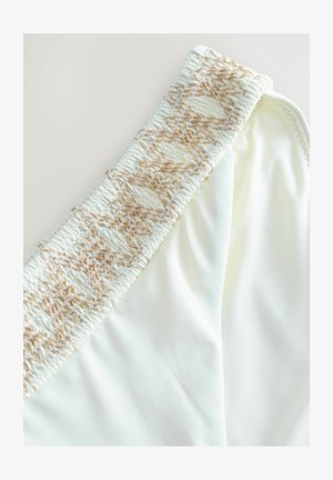 Bela kopalna spodnja del, ki ima strukturiran bež tkaninasti elastični pas. Gladka tkanina z rahlo sijočim zaključkom. Brez vzorcev ali dodatnih poudarkov.