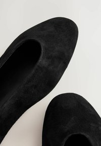 Mustat mokkanahka-asusteet, joissa on terävä kärki ja leikattu sivu. Sujuva pinta, minimalistinen muotoilu. Kevyesti teksturoitu pinta matalla viimeistelyllä.