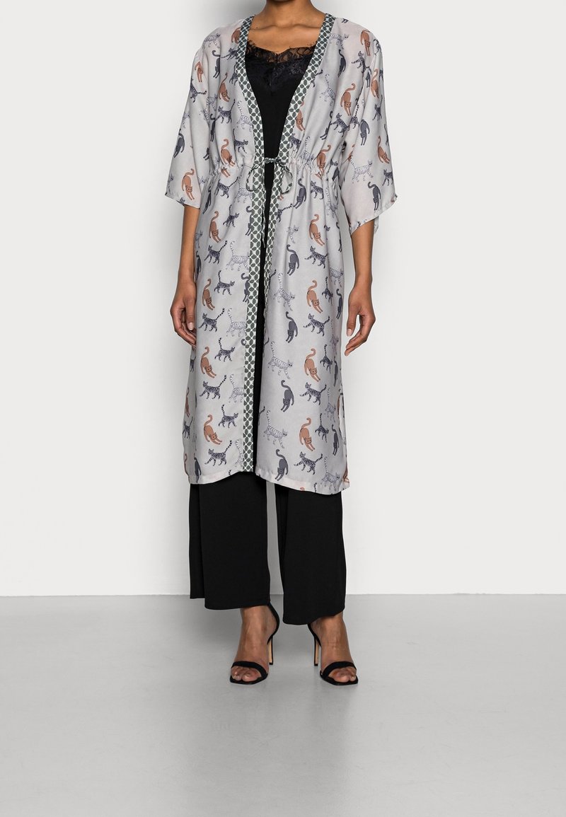Lättvikts, knälång kimono i genomskinlig grått tyg med färgglada kattmönster. Knuten i midjan med ett mönstrat kantband och vida ärmar.