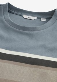 Grå bomulds T-shirt med rund hals, der har horisontale striber i beige, hvid, sort og grå nuancer. Stoffet har en glat tekstur.