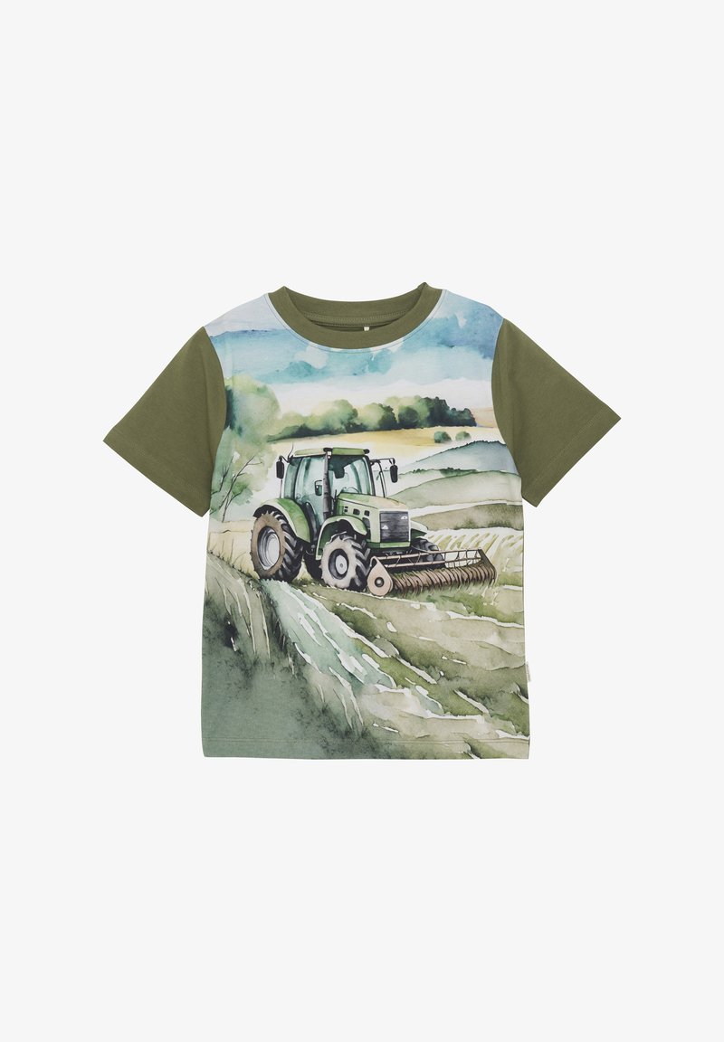 Un T-shirt à manches courtes présente un graphique de tracteur vert sur un arrière-plan de paysage aquarelle, avec une section supérieure entièrement verte.