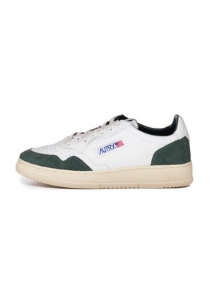 White leather sneakers with green suede accents, perforated toe, beige sole, and a blue and red logo patch on the side.