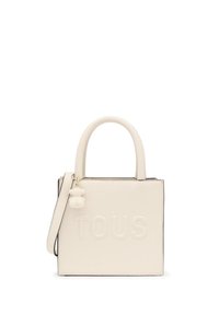 Biała skórzana torba tote z wytłoczonym logo "TOUS", górnymi uchwytami, odpinanym paskiem na ramię oraz teksturowanym akcentem w postaci breloczka w kształcie misia.