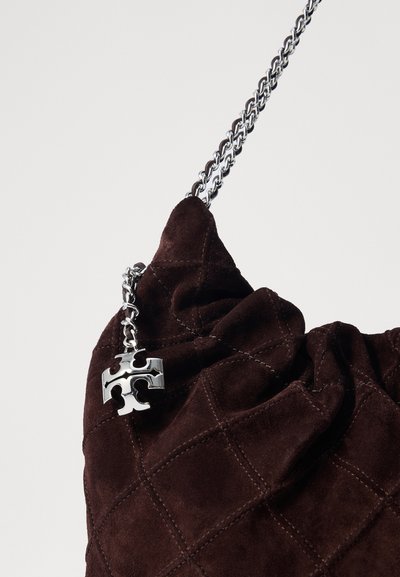 Geantă din suede maro cu un model matlasat, curea de lanț argintie și un accent sub formă de farmec în formă de piesă de puzzle. Apariție texturată și moale.