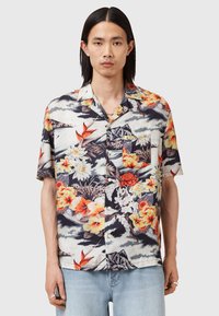 Camicetta hawaiana a maniche corte con motivo floreale e montano multicolore, base beige, e tasca sul petto con chiusura a bottone.