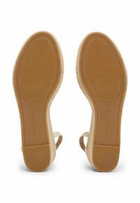 Zoccoli beige chiaro in espadrilles con suola in gomma testurizzata, accenti simili al sughero e design aperto sul retro. Nome del marchio impresso sulla suola.
