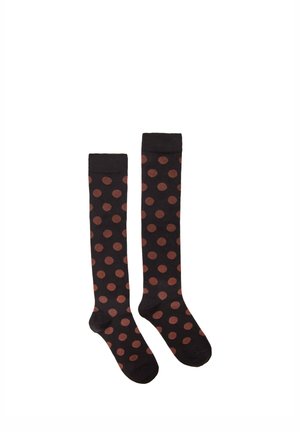 Paire de chaussettes noires montantes avec de grands pois marron espacés uniformément sur fond blanc.