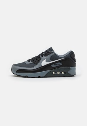 Schwarzer und grauer Nike Air Max Sneaker mit weißem Swoosh, sichtbarer Air-Cushion-Sohle und schwarzen Schnürsenkeln vor weißem Hintergrund.