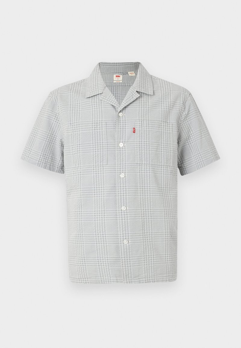 Chemise à manches courtes à boutons en motif à carreaux gris. Fabriquée en tissu léger, elle comporte une poche poitrine unique et un petit logo.
