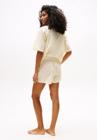 Ensemble de pyjama court à rayures jaune clair et blanches, comprenant un haut ample à manches courtes et un short, fabriqué à partir d'un tissu doux, avec une coupe décontractée.