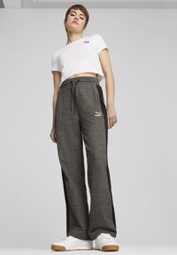 Afskåret hvid t-shirt med sort logo, parret med grå mønstrede sweatpants med sorte sidelærreder og elastisk talje. Hvide sneakers.