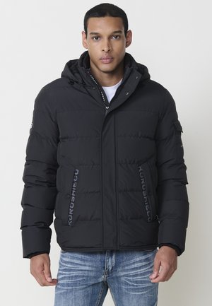 Chaqueta de plumas negra con capucha, que cuenta con cierre de cremallera, detalles del logo y un diseño acolchado. Fabricada con material sintético, ofrece aislamiento térmico.