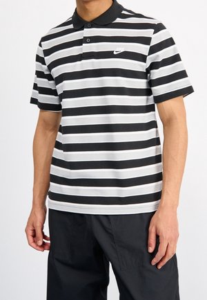 Czarna i szara w paski koszulka polo z czarnym kołnierzykiem, trzema guzikami oraz białym logo Nike po lewej stronie klatki piersiowej. Krótkie rękawy.