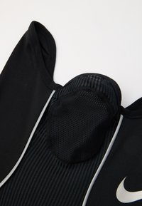 Čierne športové tričko s priedušnou sieťovinou, zaobleným výstrihom a šedými akcentmi; obsahuje logo Nike na prednej strane.