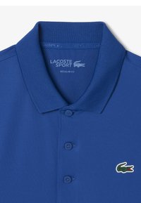 Blauwe Lacoste Sport polo shirt, normale pasvorm, met een zachte textuur, drie knopen en een groene krokodillenlogo op de linkerborst.