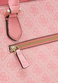 Rosa håndtaske med en belagt stof med et subtilt præget mønster, guld lynlås hardware og en tekstureret rosa læderdetalje.