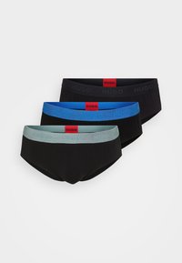 Drie paar stretch katoenen trunks in zwart met gekleurde tailles: lichtblauw, groen en zwart, met het "HUGO" logo.