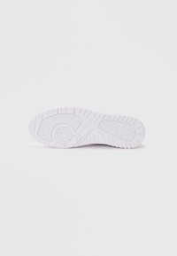 Suela de zapatilla blanca con diseño de goma texturizada, con un acento circular y ranuras para tracción. Forma plana y redonda con detalles mínimos.