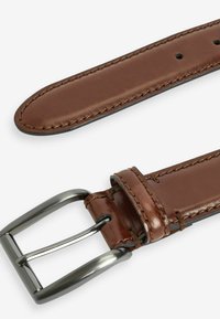 Cinturón de cuero marrón con una textura suave, que presenta una hebilla de metal en tono plateado y costuras en contraste a lo largo de los bordes.
