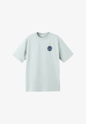 T-shirt di cotone azzurro chiaro con maniche corte, collo rotondo e un piccolo logo circolare blu navy sul petto sinistro con linee ondulate.
