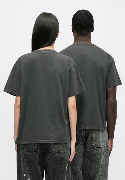 Grå bomulls-t-shirts med avslappnad passform, korta ärmar och rund halsringning, tillsammans med svarta jeans med en blekt textur.