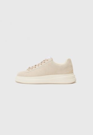 Baskets en daim beige avec une semelle plate couleur crème, dotées de lacets ronds et d'un logo sur le côté. Design simple et moderne.