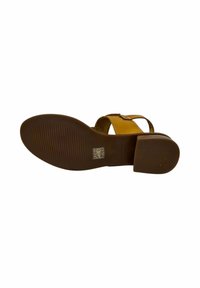 Sandalia marrón con tacón bajo en bloque, que presenta una tira amarilla y una suela texturizada. El diseño incluye herrajes ajustables y líneas sencillas.