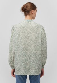 Mint green blouse with a floral pattern, long puffed sleeves, and elastic cuffs. Lightweight fabric and a classic collar design.