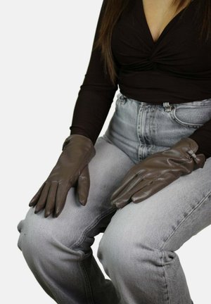 Gants en cuir marron avec une texture lisse et une coupe ajustée. Ils comportent une bande élastique discrète au poignet pour un confort ajustable.