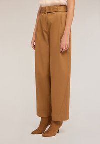 Wijde broek in een warme bruine stof, met een hoge taille en een bijpassende riem. Soepele textuur met strakke lijnen en minimale details.