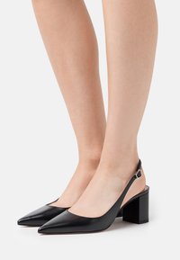 Black leather slingback heels with a pointed toe and chunky block heel, featuring a minimal design and smooth texture.
