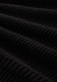 Schwarzer Strickstoff mit strukturiertem Rippmuster und glatten Wellen, der ein dichtes und weiches Material unter natürlichem Licht zeigt.