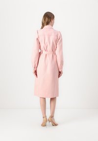 Rosa belted trench coat med lange ermer, krage og teksturert stoff. Kne-lengde design med en glatt bakside og knappedinger.