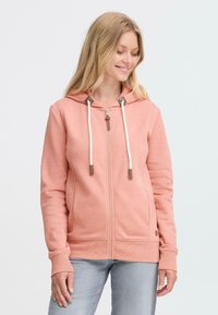 Hoodie rose clair avec une fermeture éclair à l'avant, deux poches, un cordon de serrage réglable et des poignets côtelés. Tissu doux avec une texture confortable.