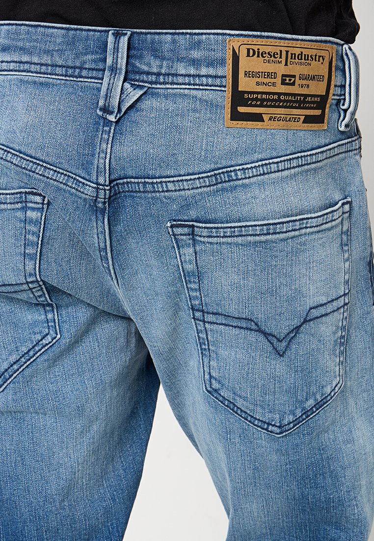 Jeans in denim azzurro chiaro con un classico design a cinque tasche, con cuciture visibili, un'etichetta in pelle del marchio e una texture sbiadita.