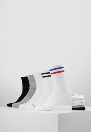 Fünf Paar Socken in einer Reihe angeordnet: schwarz, grau, weiß mit schwarzen Streifen, weiß mit blau und roten Streifen und eine gestapelte Gruppe in schwarz und grau.