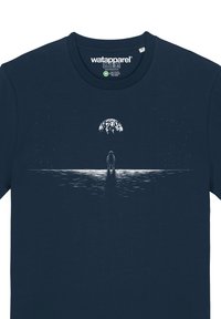 T-shirt en coton bleu marine avec un graphisme blanc représentant un astronaute debout sur une surface, avec la Terre et des étoiles en arrière-plan.