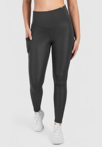 High-waisted black leggings with side pockets, made of stretchy fabric. Features a smooth texture and a form-fitting design.