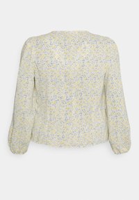 Blusa floral com um fundo amarelo e pequenos padrões de flores azuis e amarelas, com mangas bufantes longas e um corte relaxado.