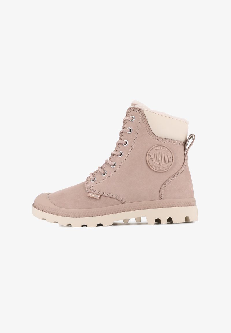 Botte en daim beige avec des accents crème, design à lacets, semelle en caoutchouc avec tread texturé, et patch logo surélevé sur le côté.