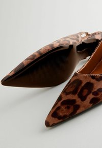 Pantofi plata cu imprimeu leopard, având un design cu vârf ascuțit, confecționați din material de suede maro și o talpă neagră texturată.
